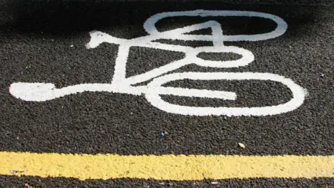 Laurence Coss/BBC White bike path symbol painted on black tarmac
