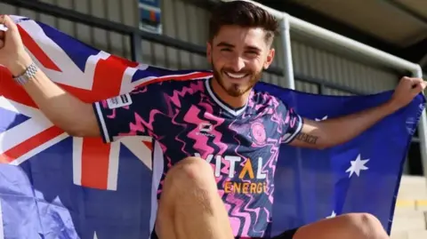 Josh Cavallo with the Australian flag after signing for Peterborough Sports