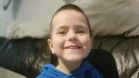 Family handout A young boy with short brown hair smiling at the camera. He is pictured from the shoulders up and wearing a blue hoodie. 