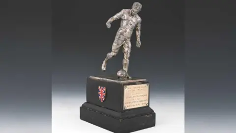 Kinghams Auctioneers The trophy has a silver statue of Sir Stanley kicking a ball on top of a stand with a bronze plaque saying: "The Footballer of the Year presented to Stanley Matthews by the Football Writers' Association Cup Final eve 1948"