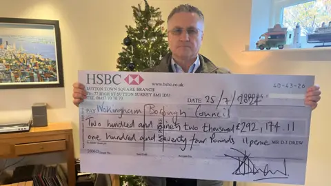 David Drew holding an over-sized presentation cheque made out to Wokingham Borough Council.
