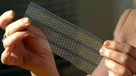 BBC A woman holds a mesh implant in her hands