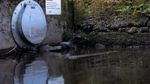A United Utilities overflow pipe near a jetty on the banks of Windermere.