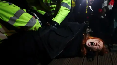 Reuters Police detain a woman as people gather at a memorial site in Clapham Common