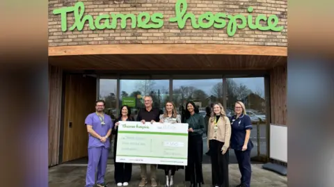 Thames Hospice Phil Laybourne is standing in a line with representatives of Thames Hospice, including its chief executive Dr Rachael de Caux 