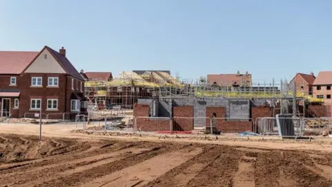 A generic image of a residential building site with red brick homes in a variety of states of development.