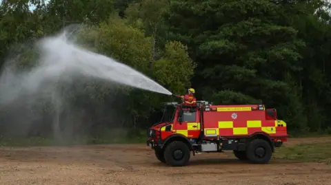 An off-road vehicle designed to tackle wildfires is used by the Surrey Fire and Rescue Service personnel during a press preview in Godalming in Surrey