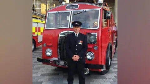 Getty Images Mark Hillier in front of a fire truck