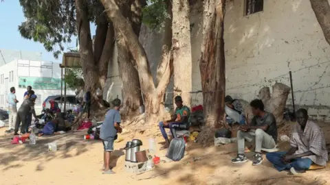 Getty Images Pengungsi dari Sudan duduk di depan kantor UNHCR di Tripoli, Libya, pada 15 Juli 2023. Tidak ada satupun gambar yang ada di artikel tersebut.