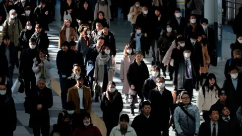 Getty Images Commuters walk on concourse at a railway's terminal station in Tokyo on January 31, 2020.