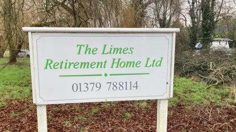 The sign for The Limes Retirement Home Ltd at the building's entrance, with grassland and trees in the background.