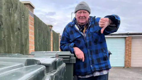 BBC Eric Polano gives the thumbs-down by green bins