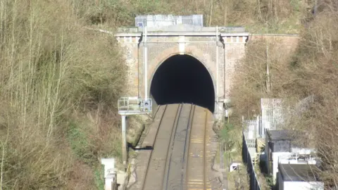 Chris Green Merstham tunnel in Surrey. The image has been taken from a bird's eye view and shows two tracks into the tunnel, which has a big arch. 