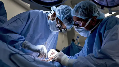 Getty Images Surgeons at work on a patient in an operating theatre