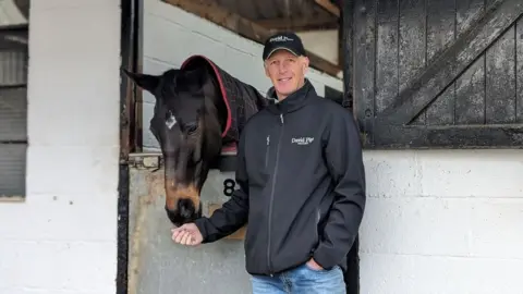 Man stood with horse at stable