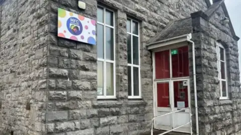 MFCA Street view shop of the outside of the new Manx Family library. It is grey-bricked. 