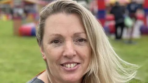 Sam Read/BBC Lady with blonde hair sitting in field.