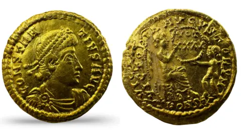 Hanson Ross The 1½ scripulum (nine-siliquae) gold coin with a man's head on it, and a Roman gold coin from the reign of Constantius II (337-361) with an image of a person on it with one arm out towards a child. 
