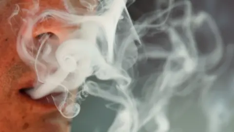 Close up of a man's mouth exhaling smoke