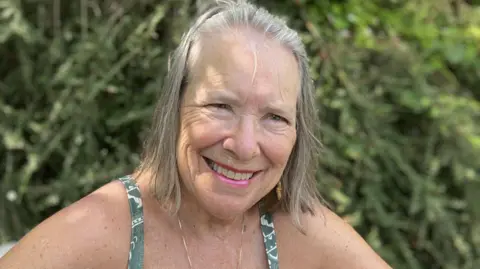 Lizzy Smart, an older woman with a grey bob, smiles at the camera 