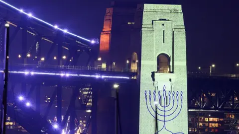 Getty Images An image of a menorah projected onto a pylon of the Sydney Harbour Bridge, which is illuminated in white light. It is night time.
