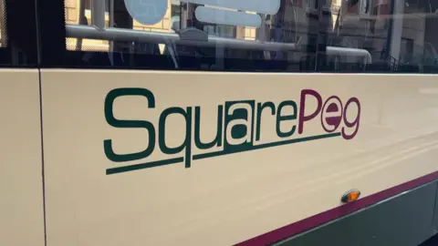 A logo on the side of a bus which reads SquarePeg.