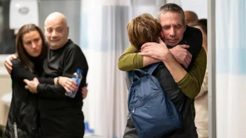 ISRAEL DEFENSE FORCES Louis Har (2nd L) and Fernando Marman (R) hug members of their families at Sheba Medical Center in central Israel