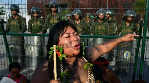 Getty An indigenous woman protests in front of a line of soldiers. 