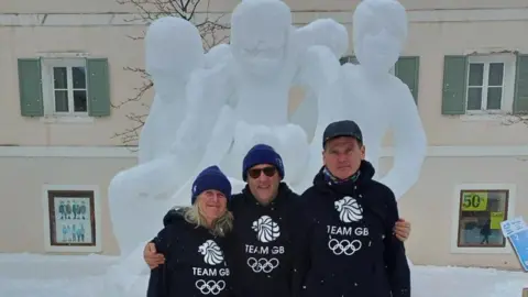 Pippa Unwin and her snow carving team mates Patrick and Dave wearing black team GB hoodies, stood infront of their snow sculpture. 