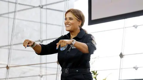 Getty Images A woman standing onstage, wearing dark clothing.