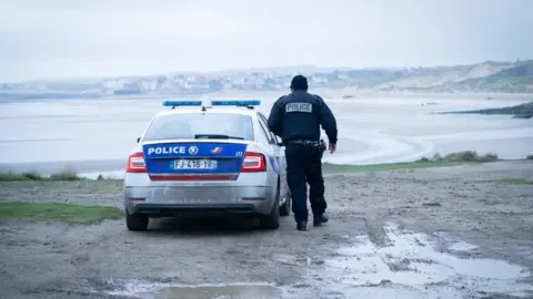 A French police officer looks out over a beach near Wimereux (file photograph)