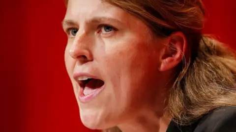 A close-up of Rachael Maskell's face as she speaks. She is standing in front of a red wall. 