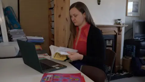 Martyna sits at her laptop reading a text book. There are other books in the background and one in the foreground. 