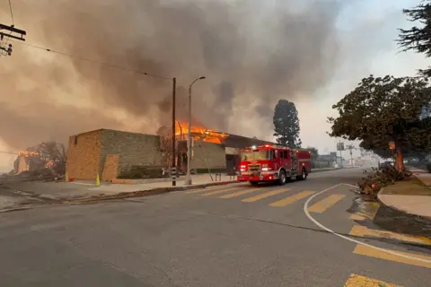 Bellocqimages/Bauer-Griffin/GC Images A fire engine goes down Sunset Boulevard as a skyscraper in the background and smoke rises Wednesday.