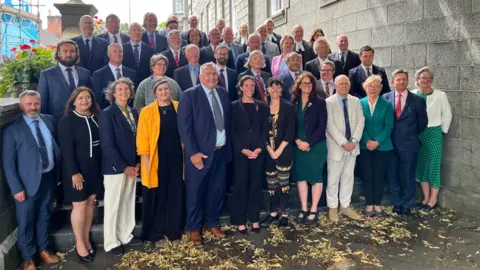 A group photo of the new States of Deliberation. The members are stood in five tiers.