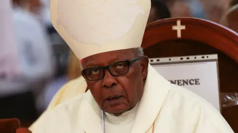 Cardinal John Njue in white clergy robes and mitre