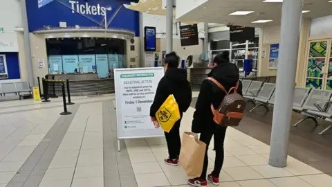 Pacemaker People looking at a board informing passengers of industrial action