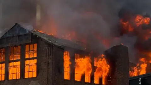 Image shows the inside of Hotspur House, a brick-built Victorian building, raging with fire. Everything inside the frames of the windows burns bright orange. 