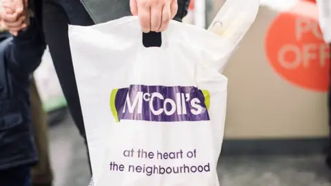 McColl's Person carrying a McColl's branded bag