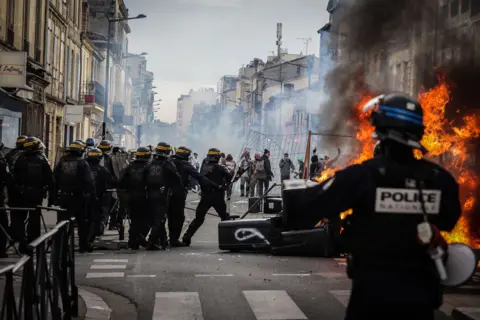 Moritz Thibaud/ABACA/REX/Shutterstock Protesters clash with riot police during a demonstration, a week after the government pushed a pensions reform through parliament without a vote, using the article 49.3 of the constitution, in Bordeaux, south western France, on March 23, 2023.