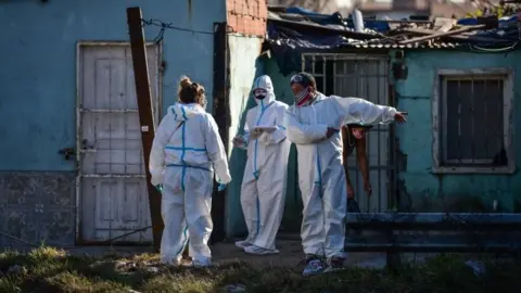 Getty Images Employees of the Ministry of Health wearing PPE carry out tests of Covid-19 to residents at Villa Itati