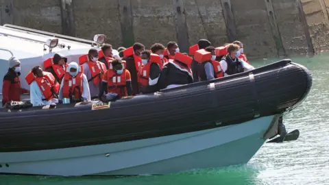 PA Media A group of people are brought in to Dover, Kent, by Border Force officers following a small boat incident in the Channel