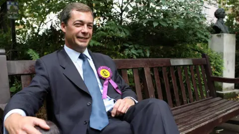 PA Nigel Farage sitting on a bench