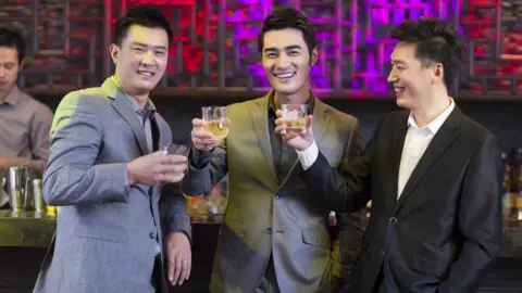 Getty Images Young friends toasting in a bar - Beijing, China - stock photo