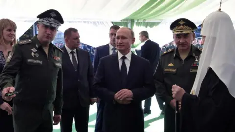 Reuters Russia's deputy defence minister Timur Ivanov stands in military uniform talking to President Vladimir Putin. Defence minister Sergei Shoigu is also present
