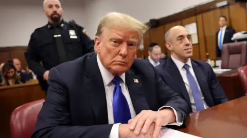 Trump sitting at the trial, looking into the camera