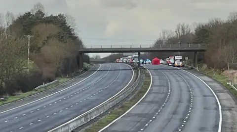 An empty motorway with emergency services and queuing traffic behind it