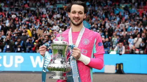 Manchester City goalkeeper James Trafford holding the FA Cup trophy at Wembley Stadium