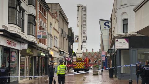 A police tape is visible in Ipswich town centre and police officers stand on the pavement