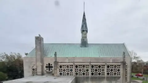 LDRS Image shows the church. It is built in grey stone, with a verdigris roof 